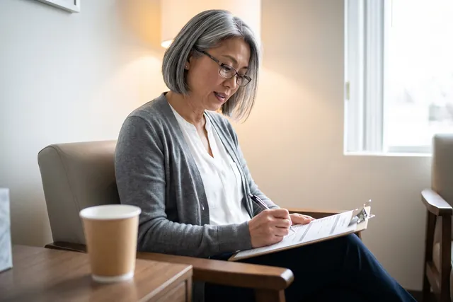 AI-generated illustration of a woman in reading glasses filling out a health history form on a clipboard in a treatment room